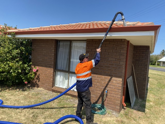 Technician using gutter vacuum system safely from the ground